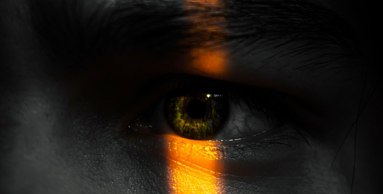 A photo of an eye of a person in the shadows.