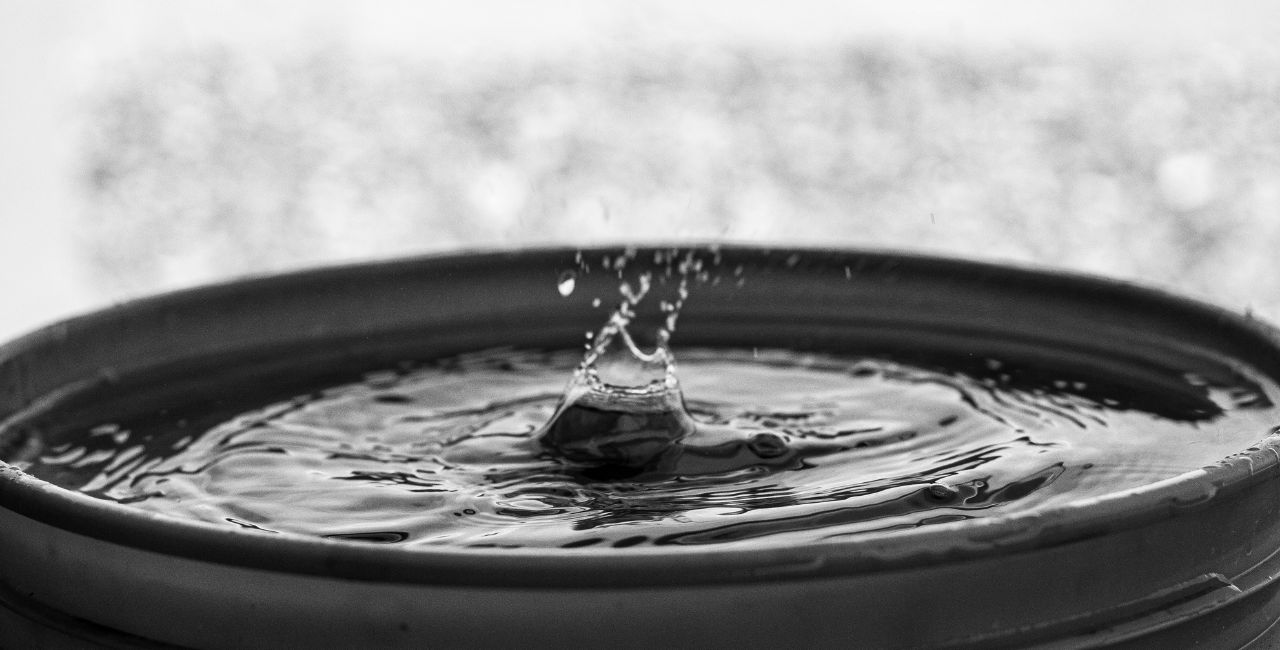 A drop of water falling into a bucket filled with water.