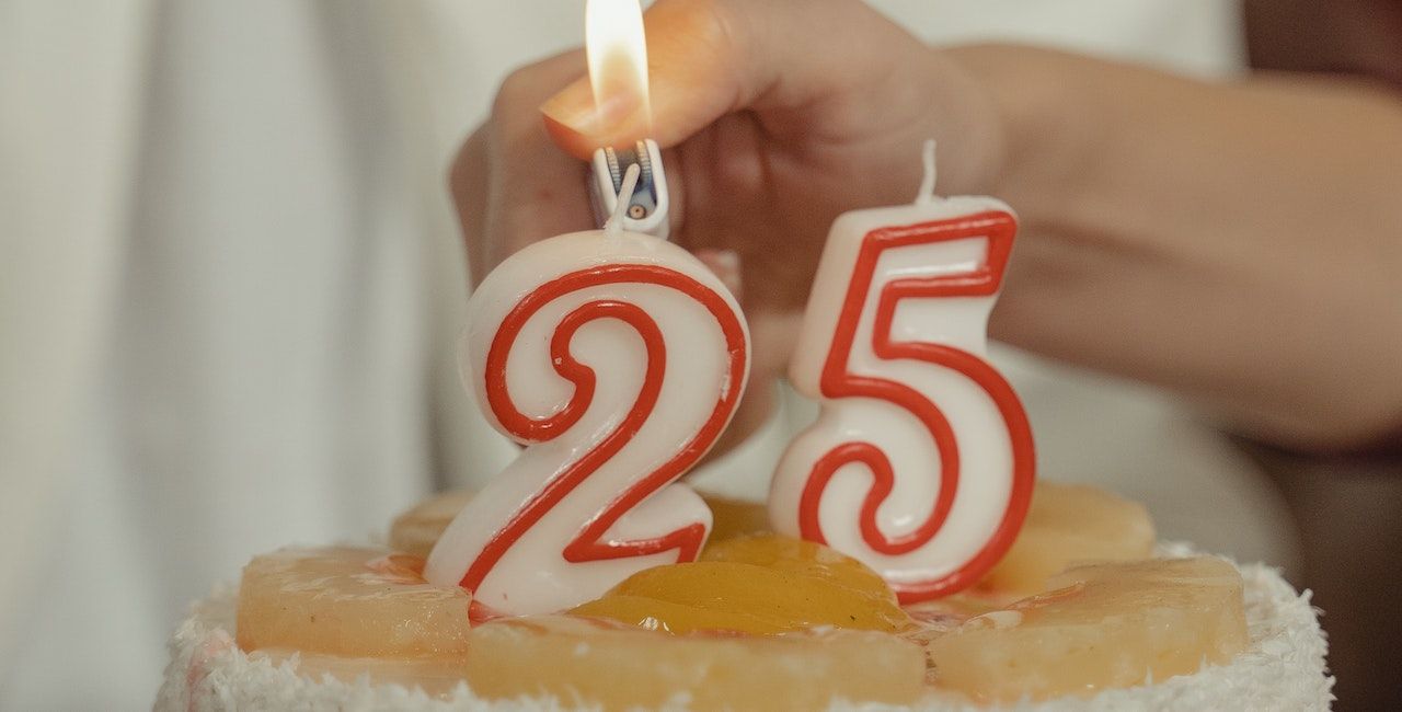 A photo of a 25 number candle being lit on a birthday cake.